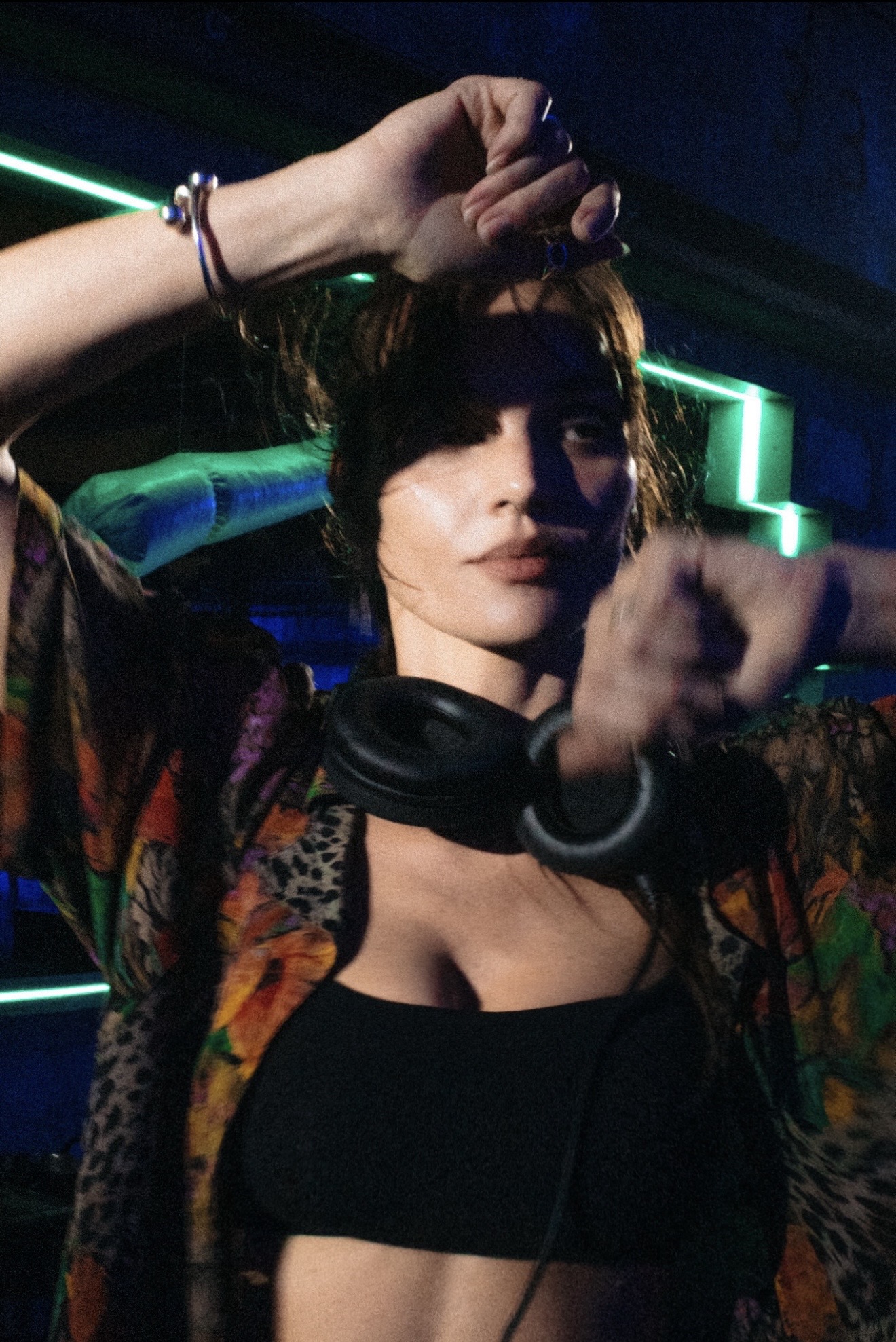 Allie Crandell, GODISOUND, with headphones around her neck under neon club lights